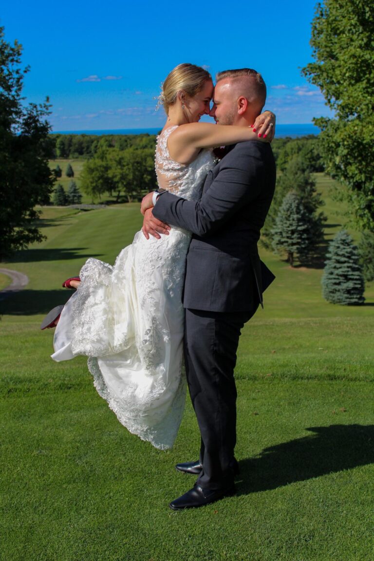 groom holding bride in front of blue sky