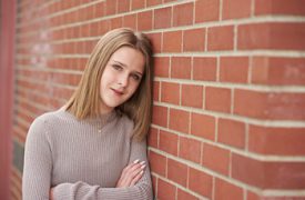 girl posed against brick wall